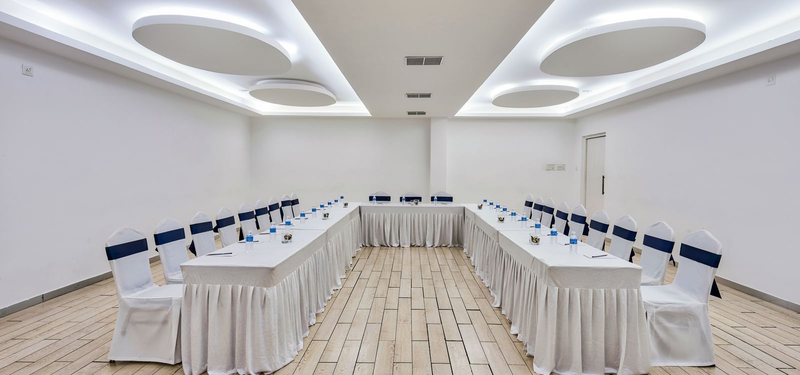 Conference hall setup with rows of tables and white chairs facing forward at Grande Bay Resort & Spa.