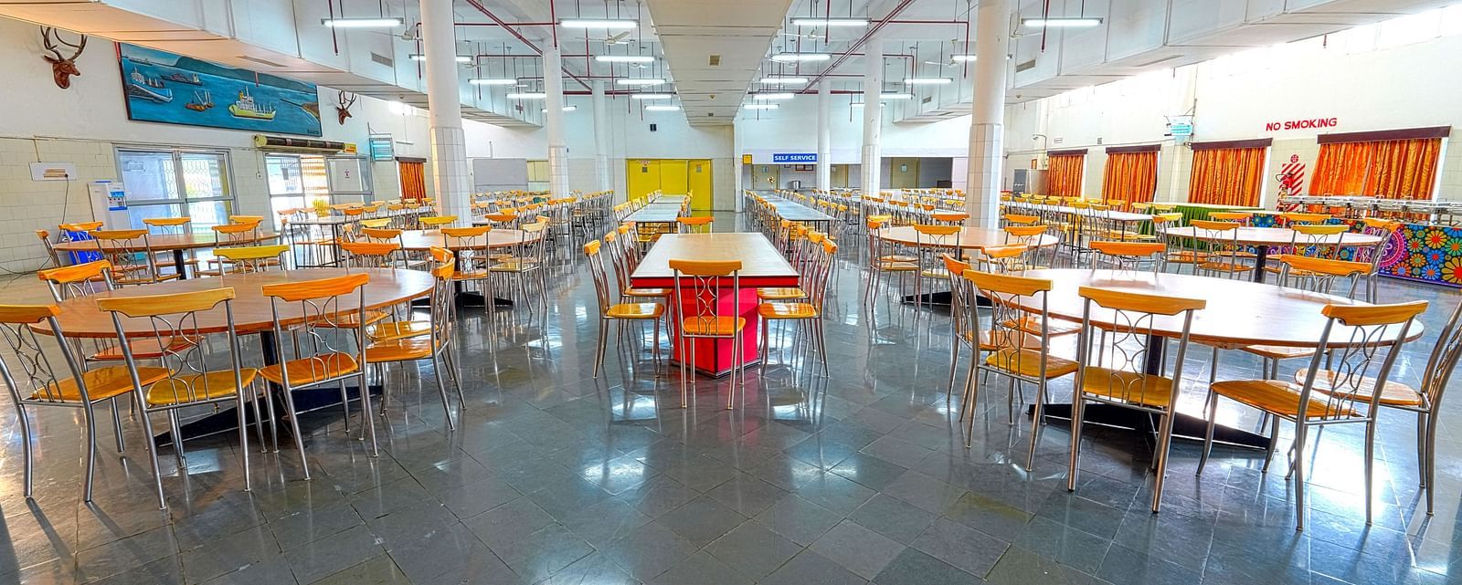 A cafeteria with many tables and chairs and a common table at the center at Sahara - Social Dining in Hyderabad.