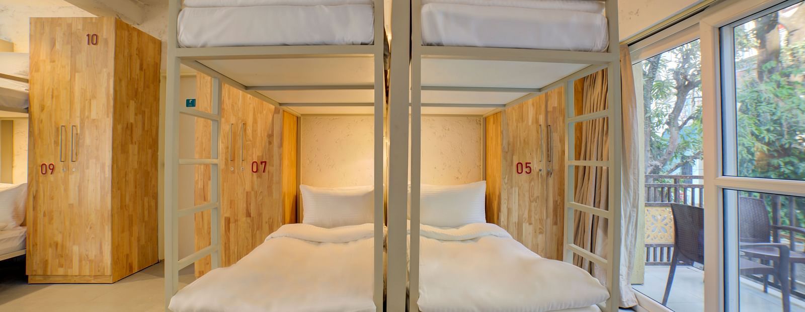 Four Bunk Beds side by side with a large window opening into a balcony on the right side - Bedzzz, Rishikesh