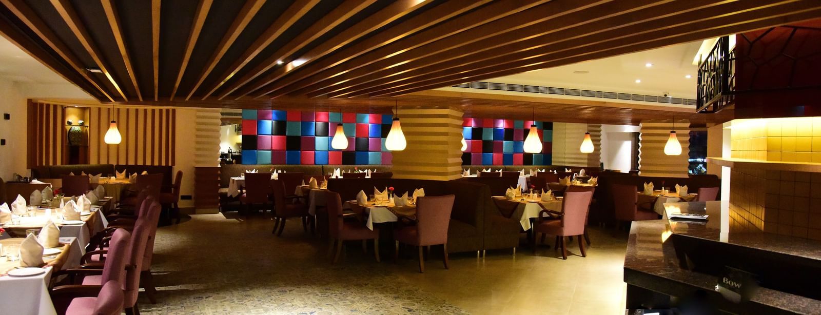 A wide-angle shot of a hotel restaurant at The Royal Comfort, with elegant lighting, tables set for dinner, and a warm atmosphere.