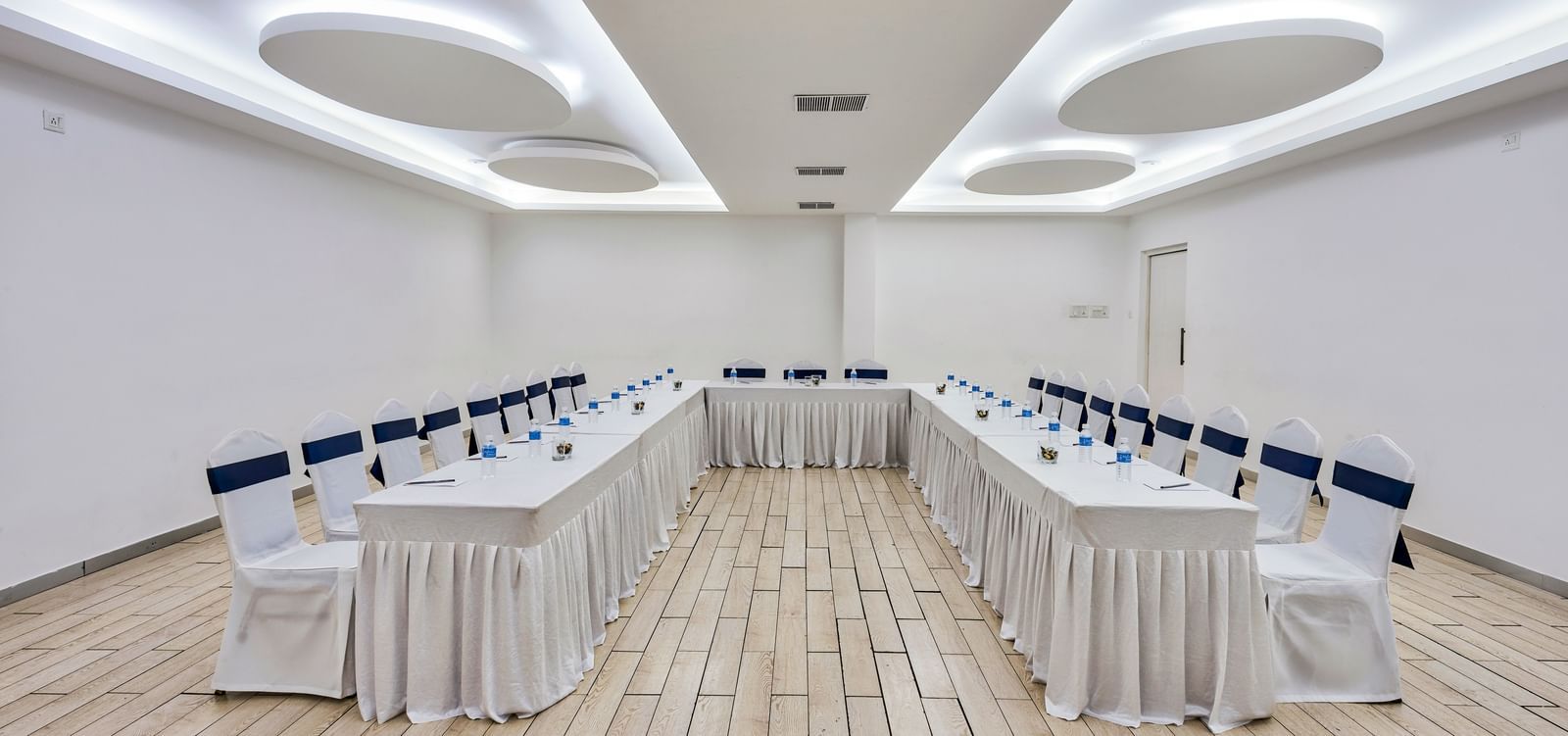 Conference hall setup with rows of tables and white chairs facing forward at Grande Bay Resort & Spa.
