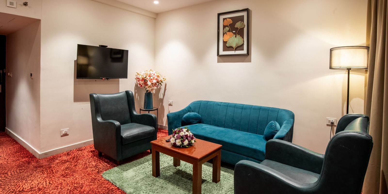 Living area with sofa seating, television, and floor lamp at Hotel Royal Regency Chennai