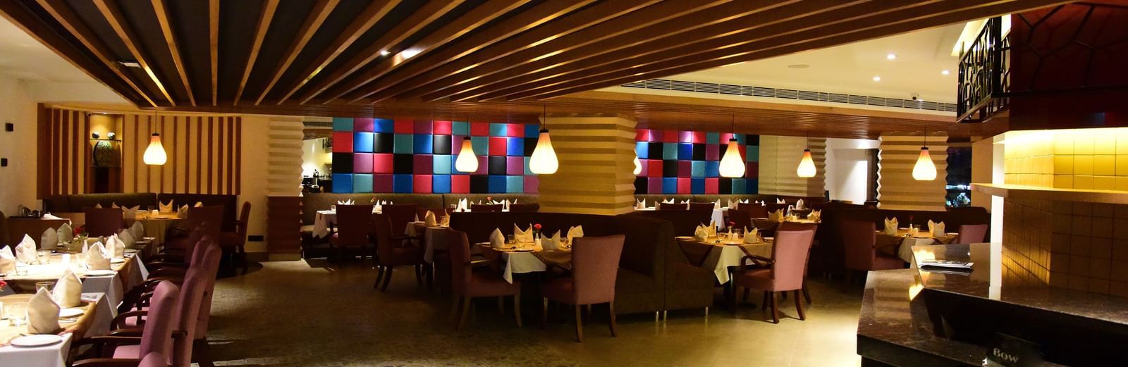 A wide-angle shot of a hotel restaurant at The Royal Comfort, with elegant lighting, tables set for dinner, and a warm atmosphere.