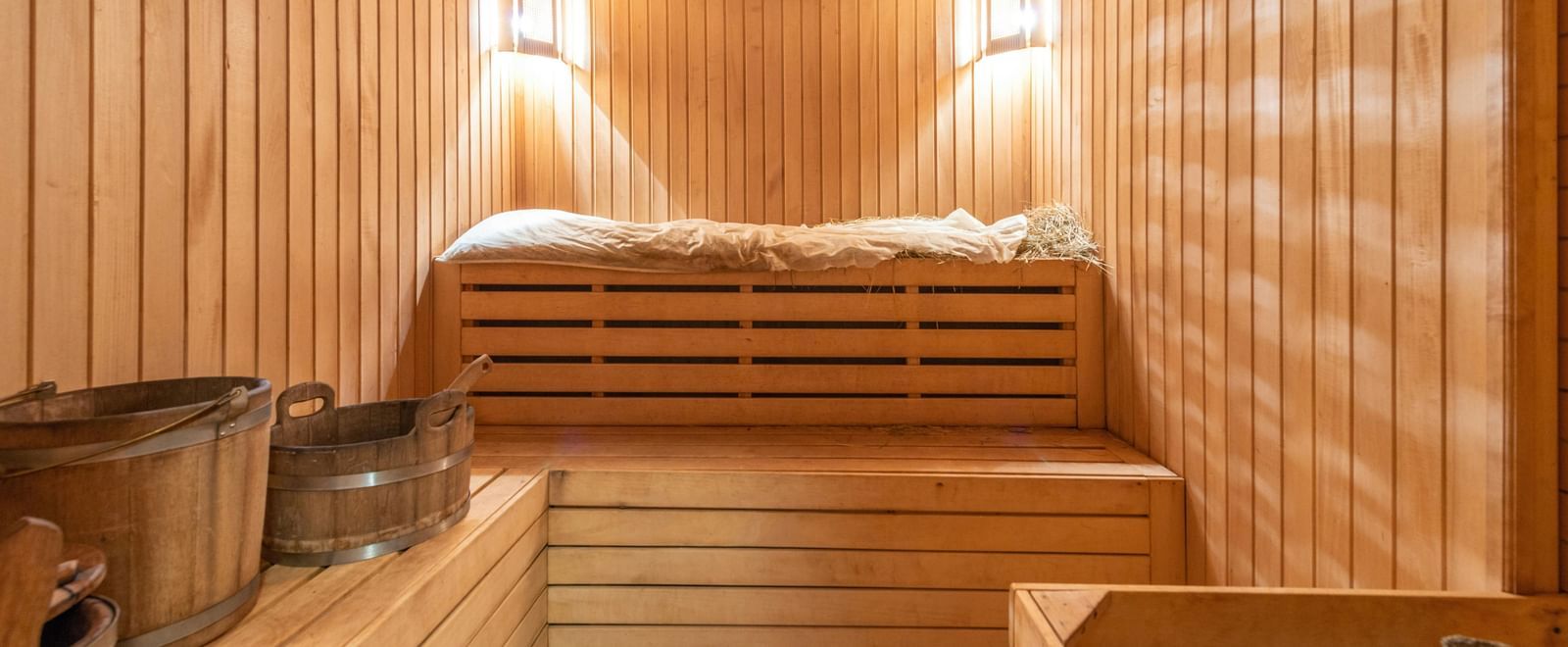 A steam room with wooden interiors and steel utensils, warmly lit.