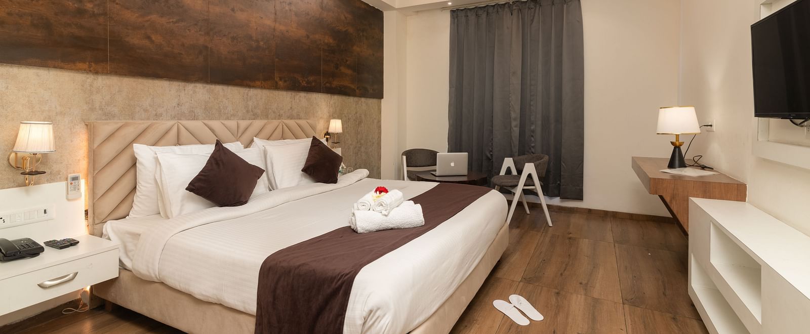 An image of a deluxe room with a work desk, chair, bed, flat screen TV, and other room amenities - DLS Ganga Bliss, Haridwar