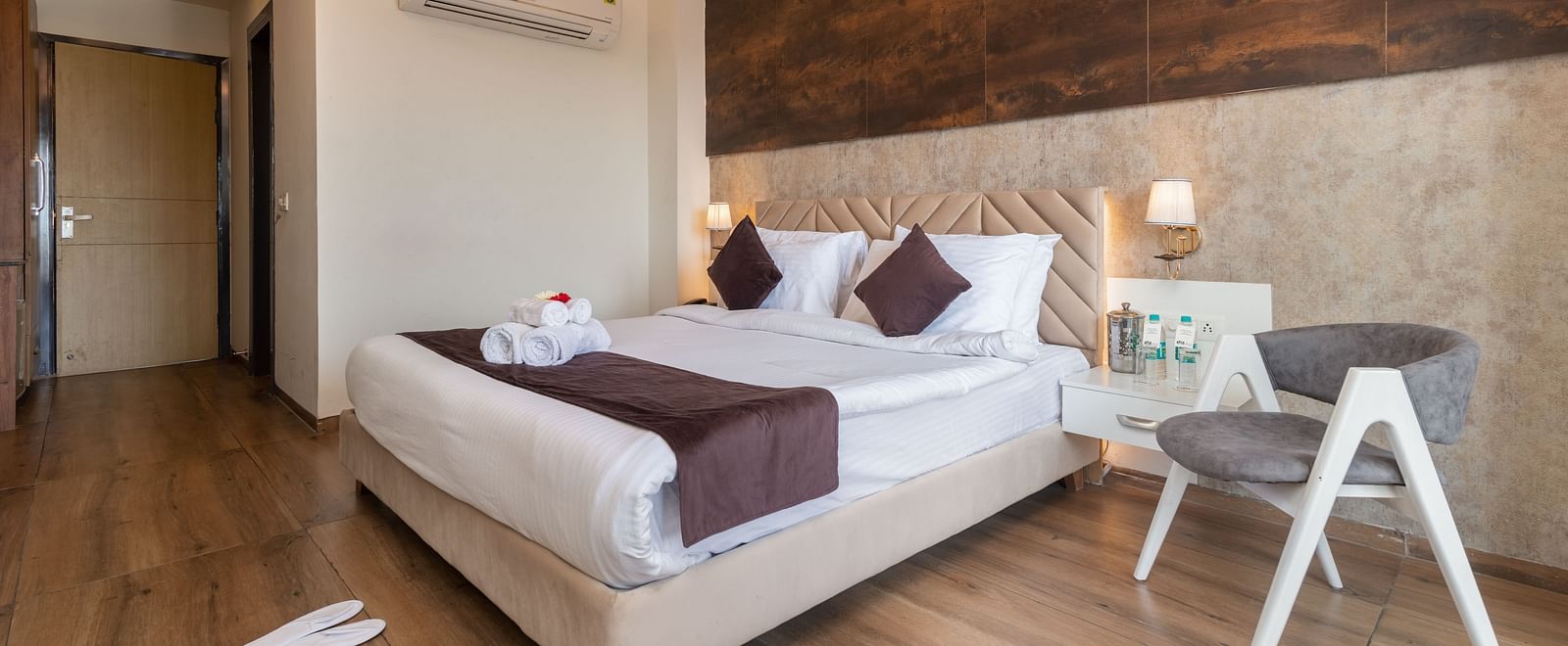 An image of the deluxe room featuring a bed with pillows and cushions, bed side tables, a chair and warm lighting - DLS Ganga Bliss, Haridwar