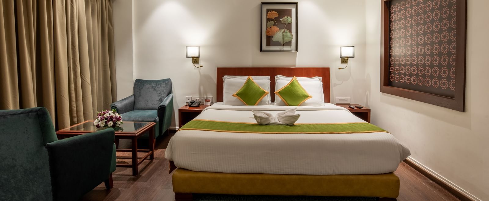 Well-lit room with king size bed, seating area, and framed artwork at Hotel Royal Regency Chennai