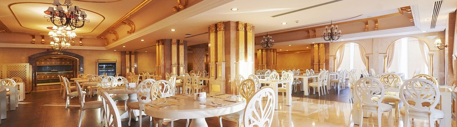 Chairs and tables in a well-lit dining space with dangling chandeliers