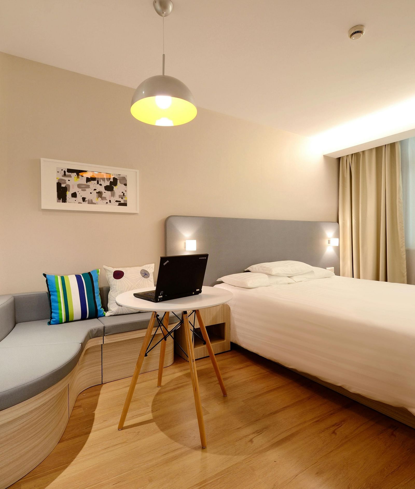 A hotel room with a single bed and work desk and chair