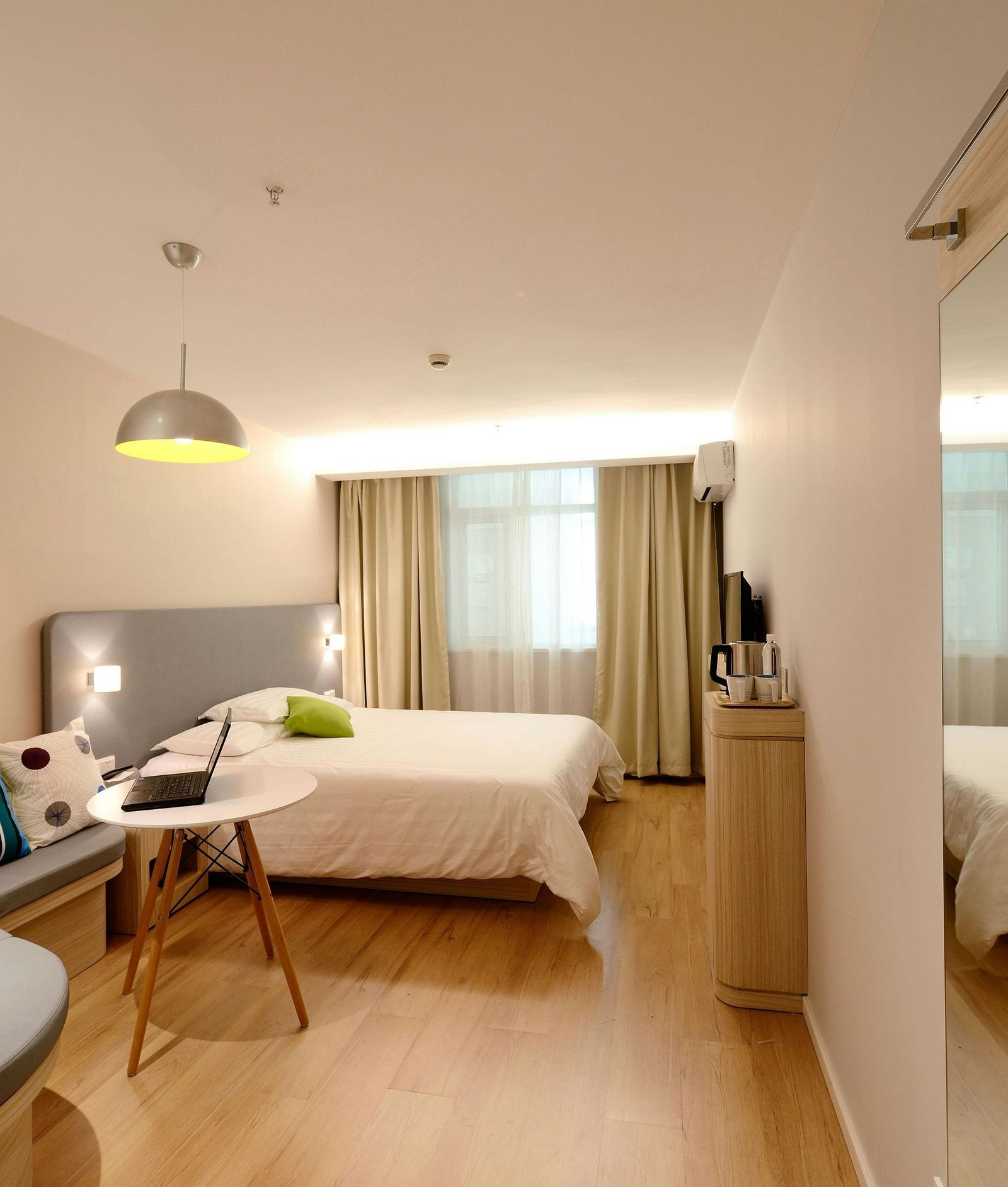 A hotel room with a double bed and a work table and chair