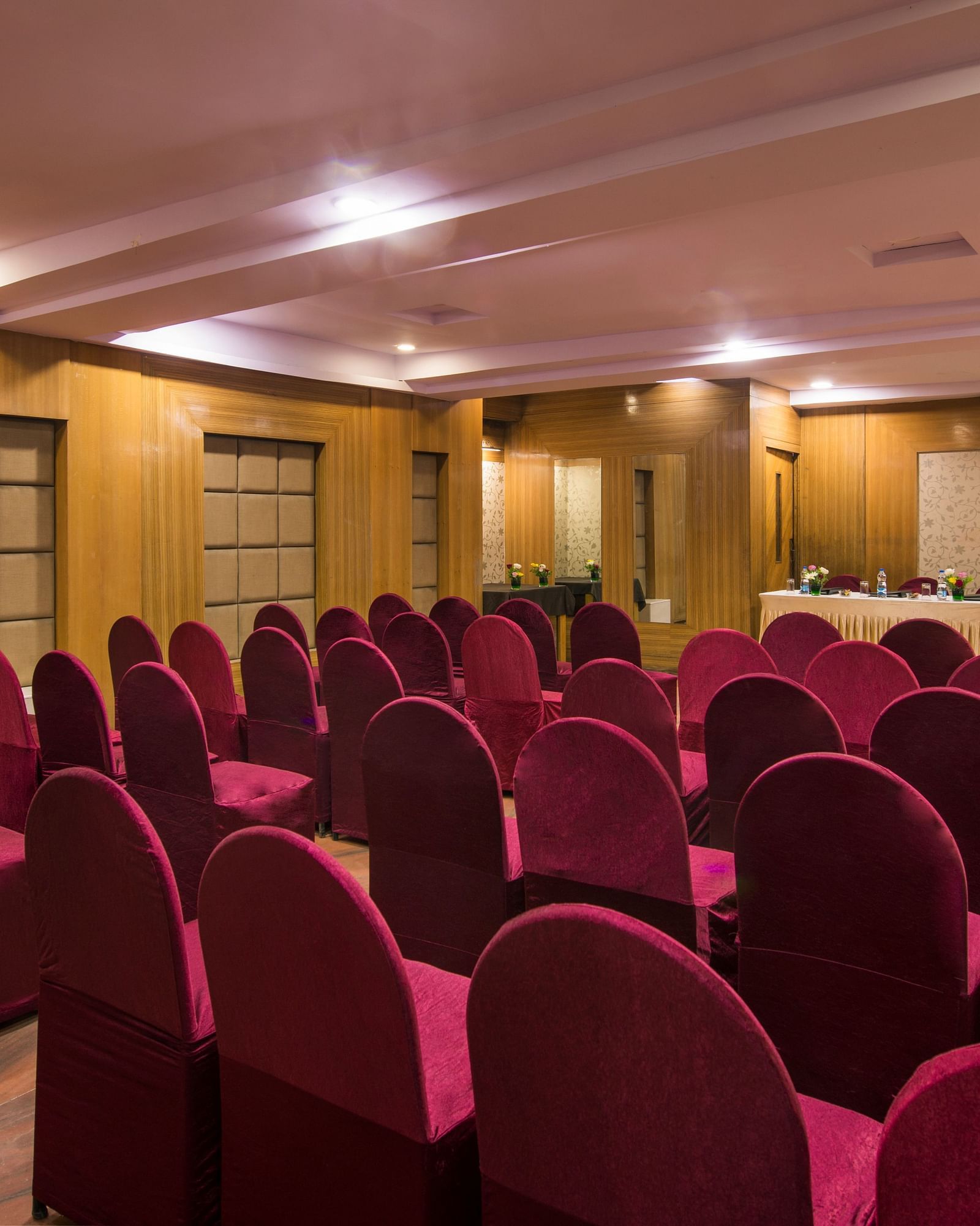 A hotel conference room with rows of red chairs facing a stage area - Lords Eco Inn Dahej