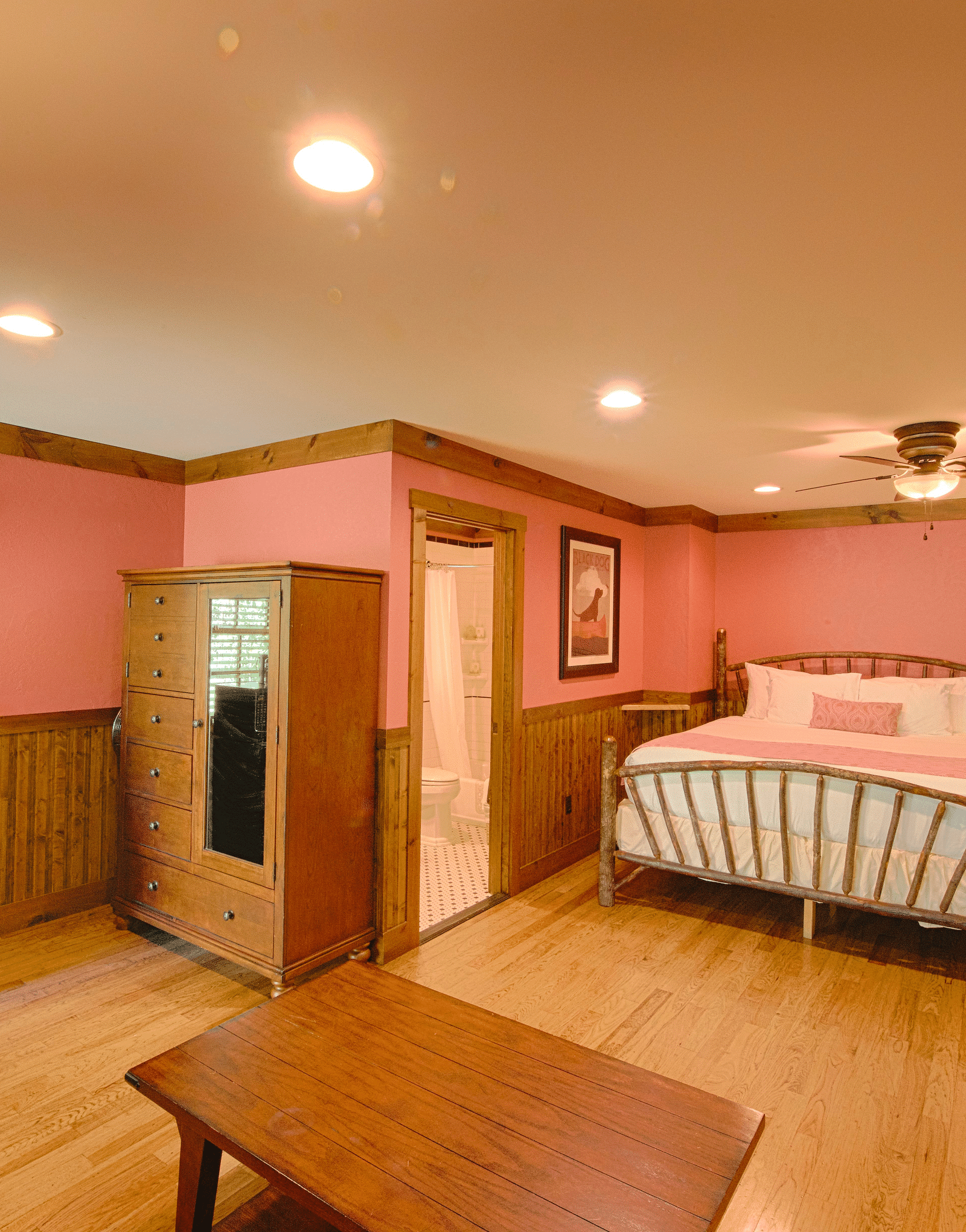 a brightly lit room with pastel pink colored walls featuring a double bed, wardrobe and a center table - Historic Tapoco Lodge