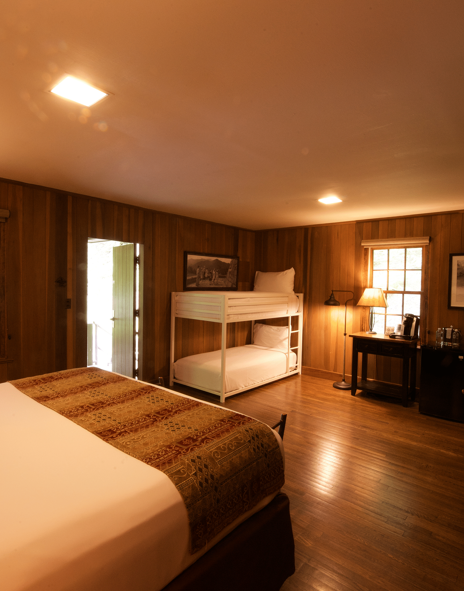 corner view image of a dimly lit bedroom featuring a double decker bunk bed and a double bed - Historic Tapoco Lodge