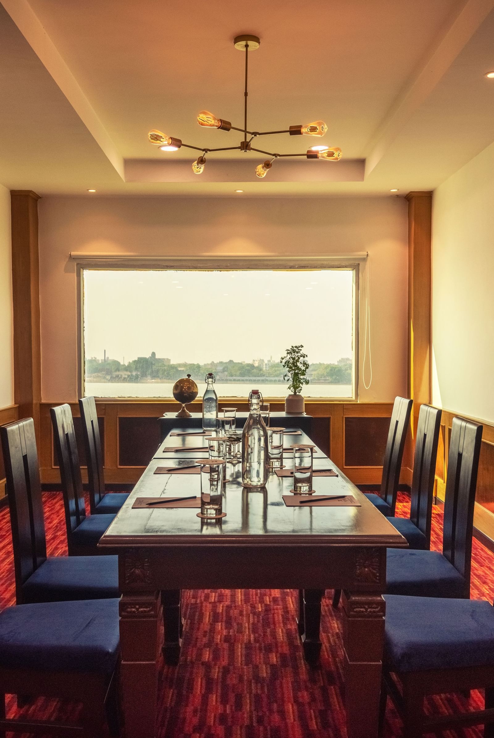 Elegant dining room at Polo Floatel with a large table, modern lighting, and a window offering scenic views.