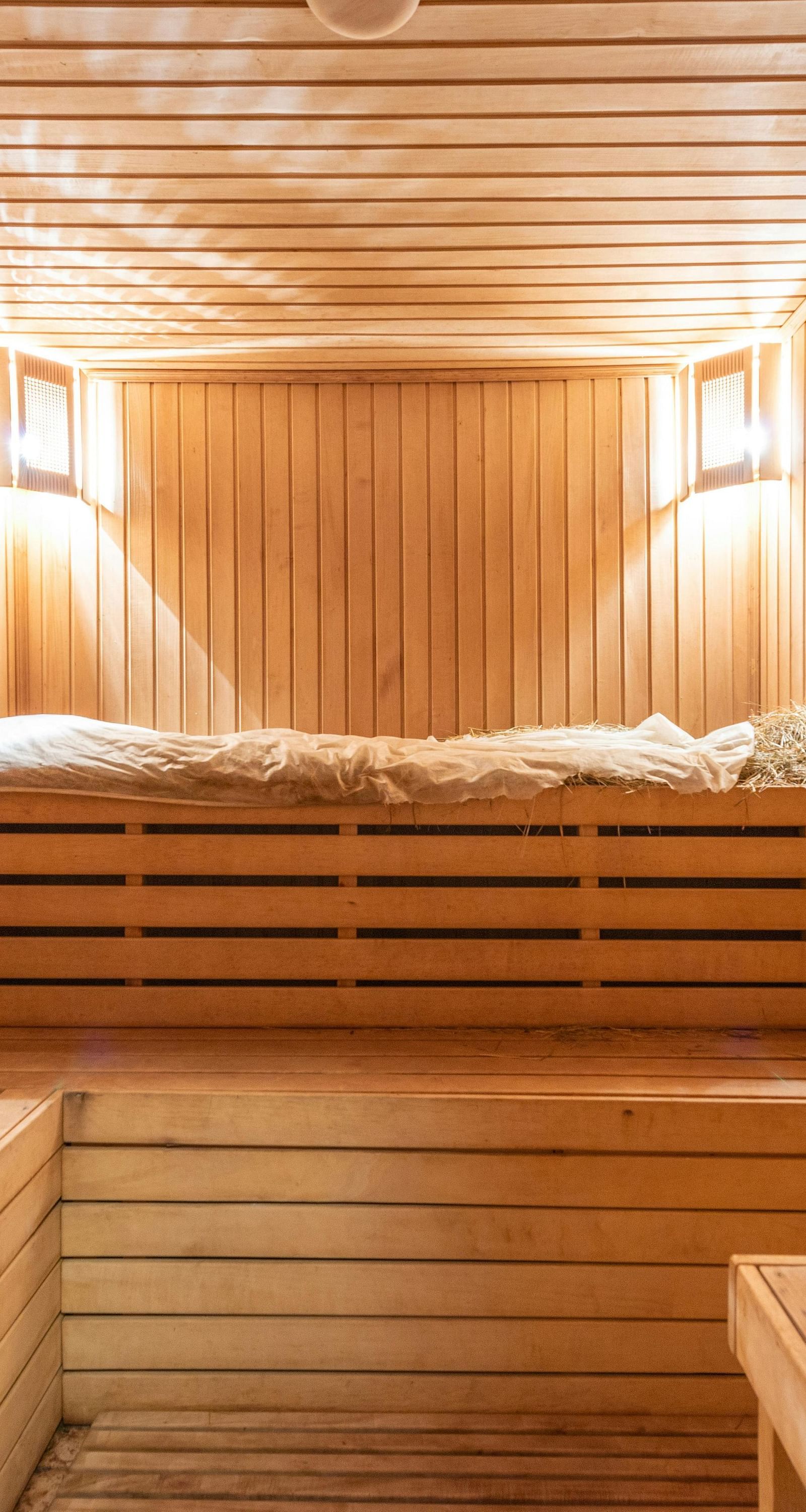 a wooden sauna room with two warm lights mounted in the corner of the ceilings