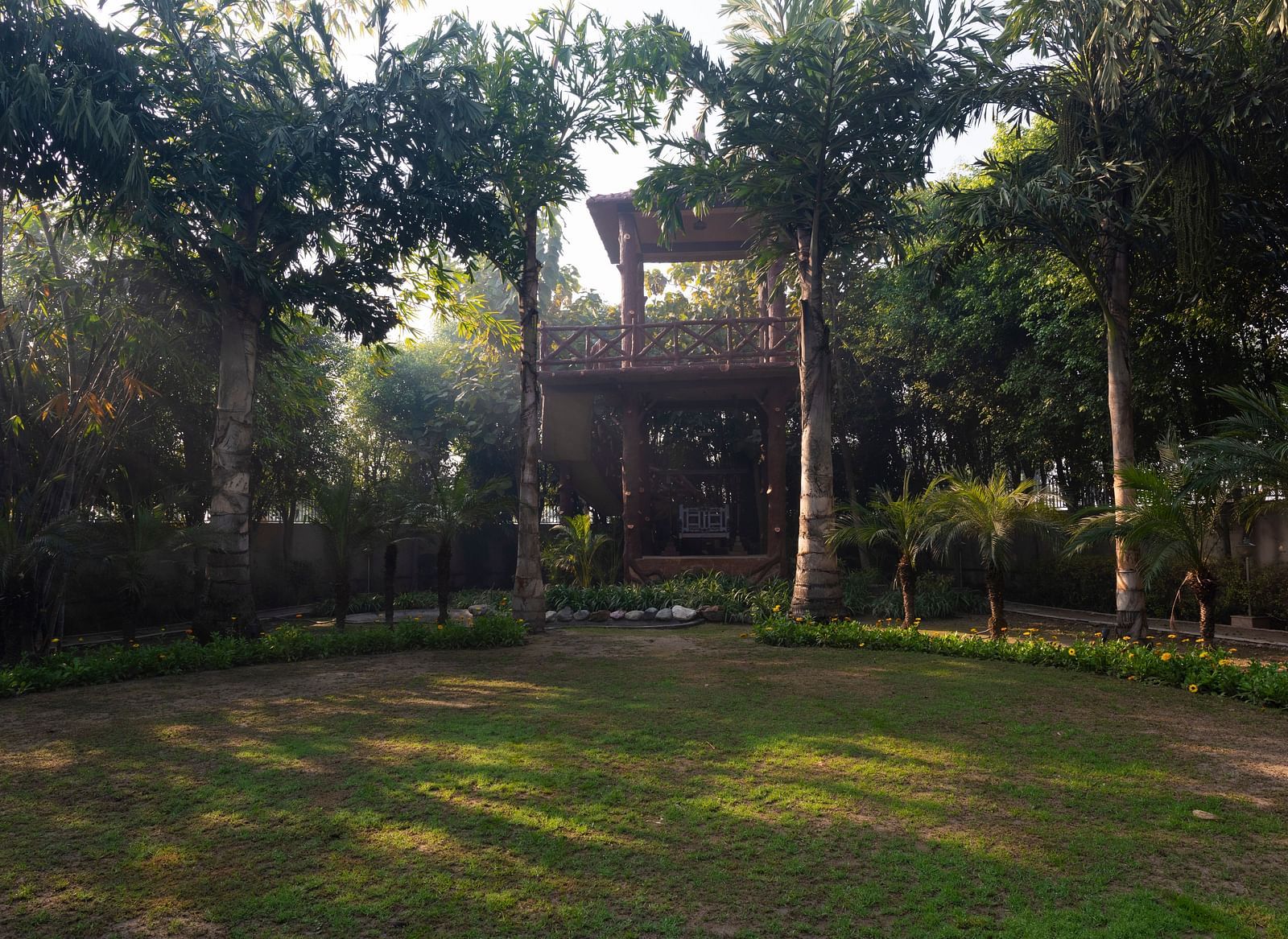 An image of a garden surrounded by tall trees at BluSalzz Resort.