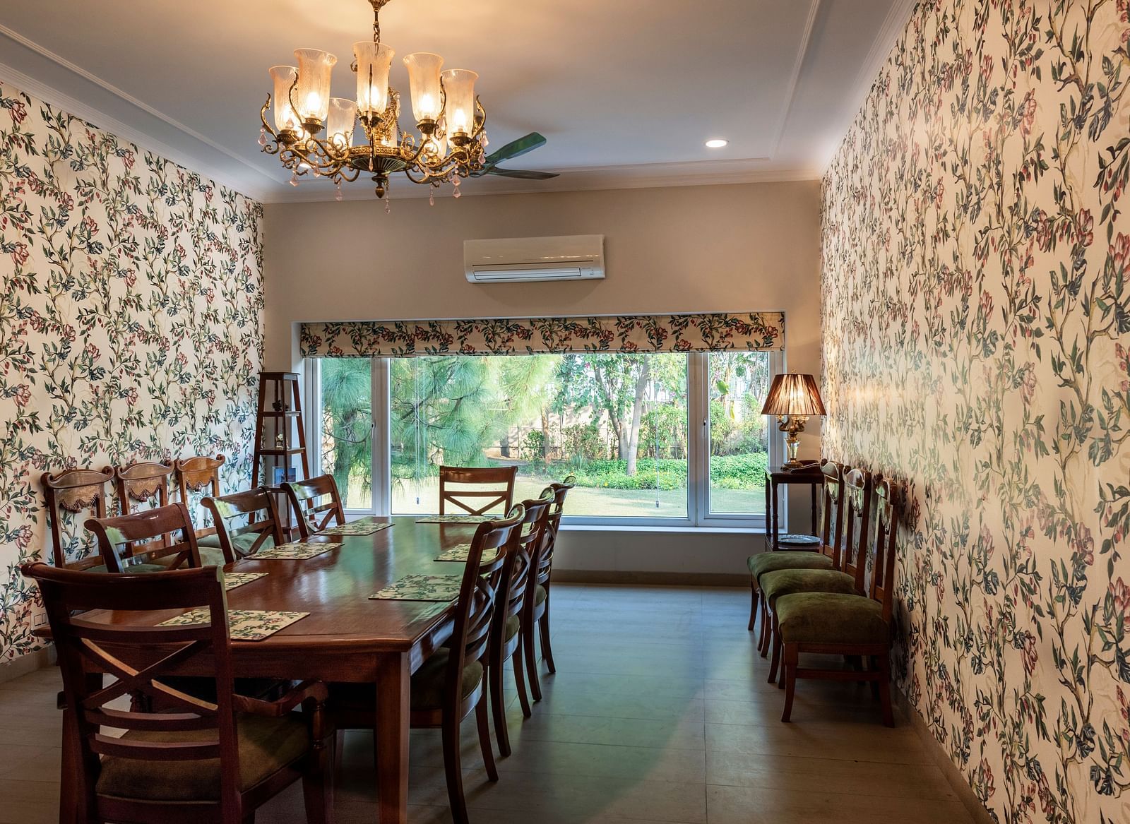 An image of a dining room with floral walls, a chandelier and an AC in the background.