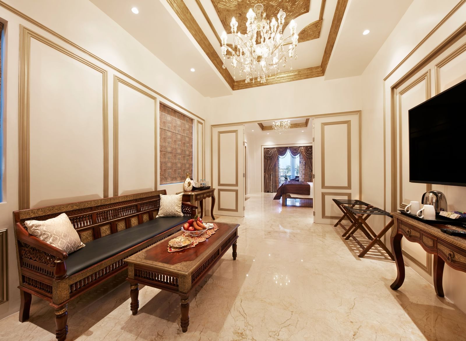 A seating area with an ornate chandelier, vintage furniture, and polished wooden flooring - Kaldan Samudhra