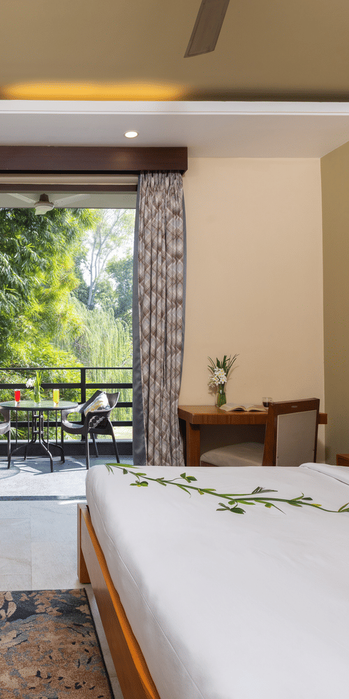  bedroom with a large bed, a seating area, and an open view to an outdoor patio  at The Golden Tusk, Jim Corbett