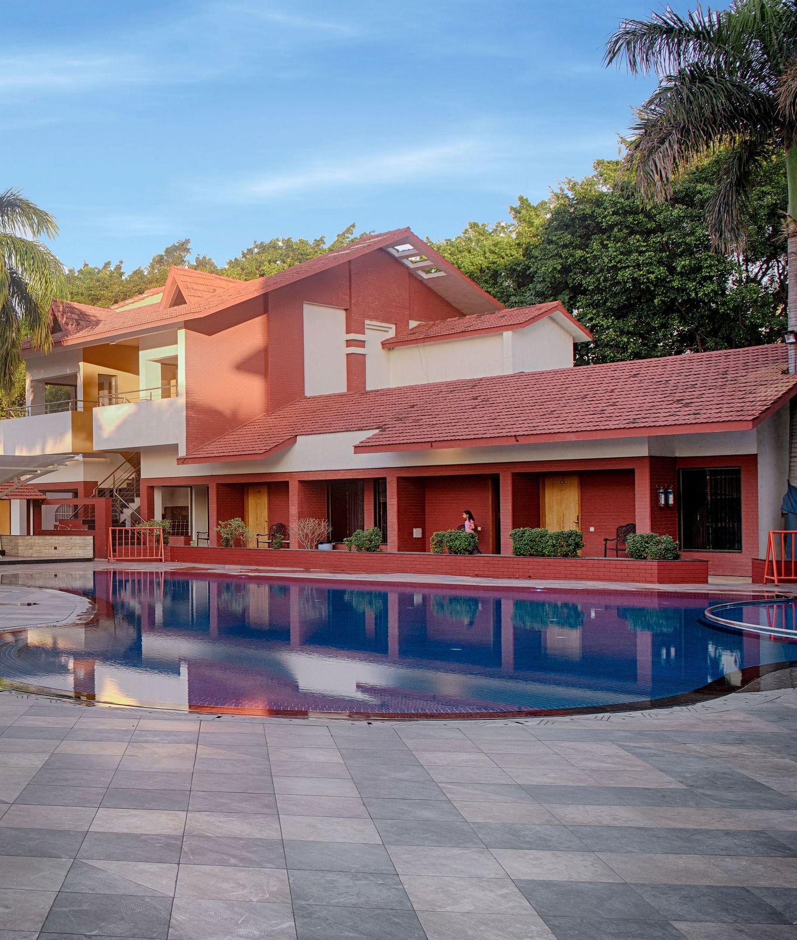 A large building beside a designer swimming pool, and coconut trees peaking behind the setting - Crescent Resorts
