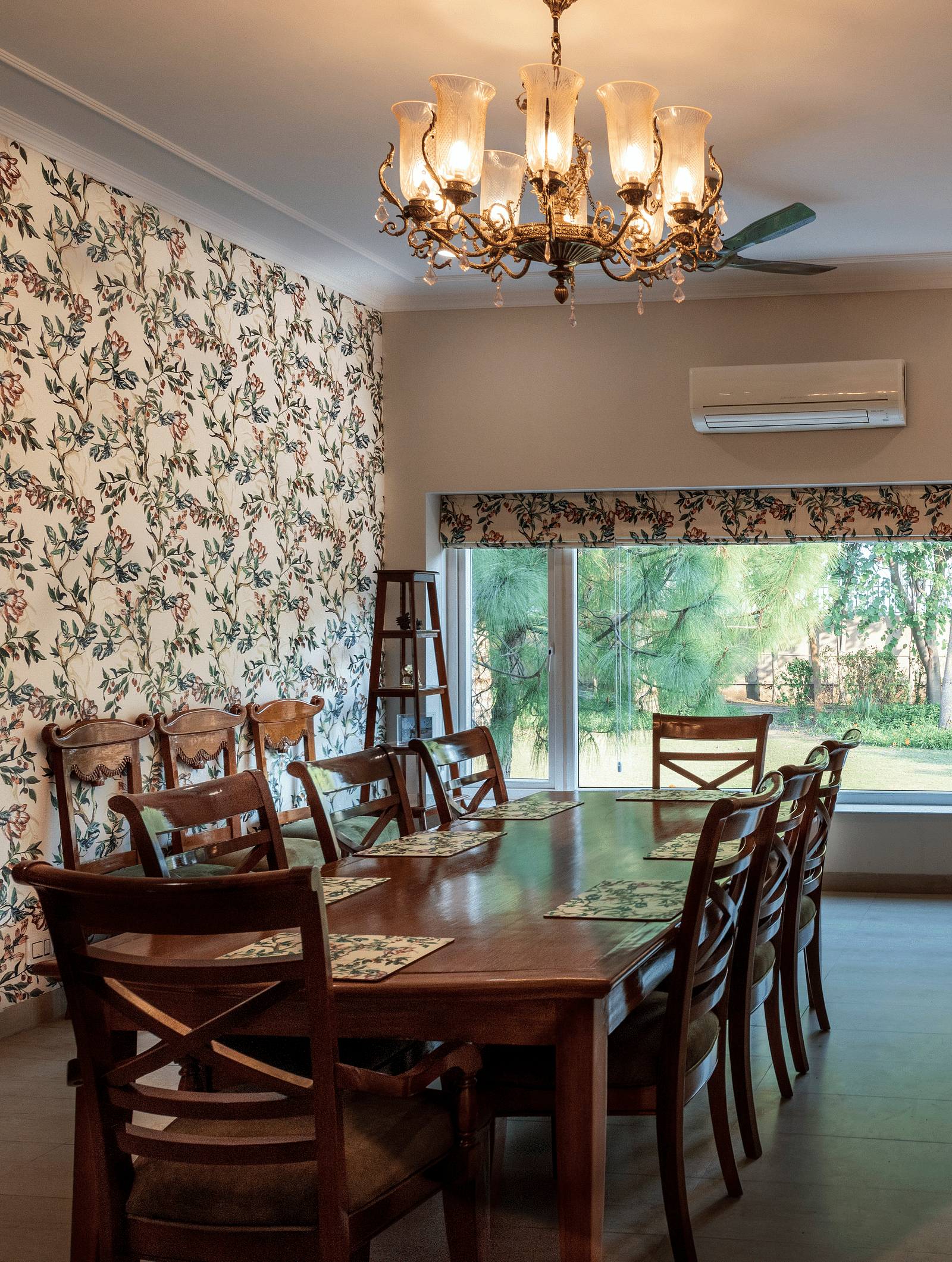 An image of a dining room with floral walls, a chandelier and an AC in the background.