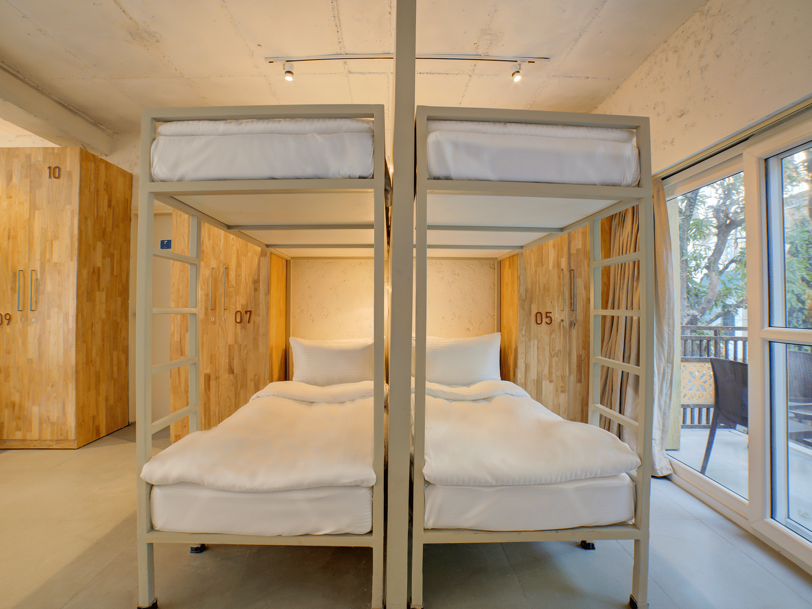 Four Bunk Beds side by side with a large window opening into a balcony on the right side - Bedzzz, Rishikesh