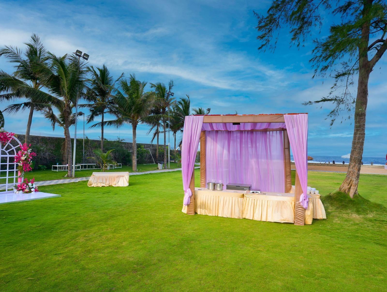 A decorated buffet space in a lawn with green trees under the blue sky at Grande Bay Resort & Spa.