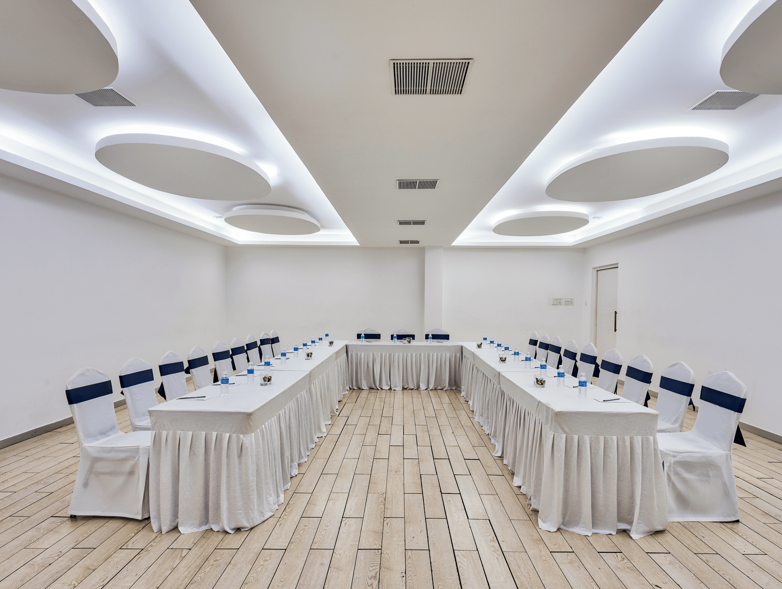 Conference hall setup with rows of tables and white chairs facing forward at Grande Bay Resort & Spa, Mamallapuram.