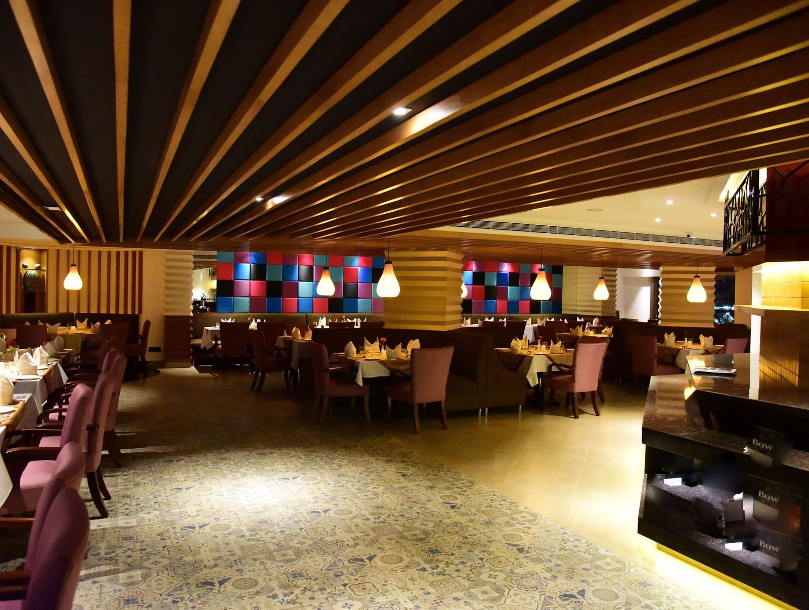 A wide-angle shot of a hotel restaurant at The Royal Comfort, with elegant lighting, tables set for dinner, and a warm atmosphere.