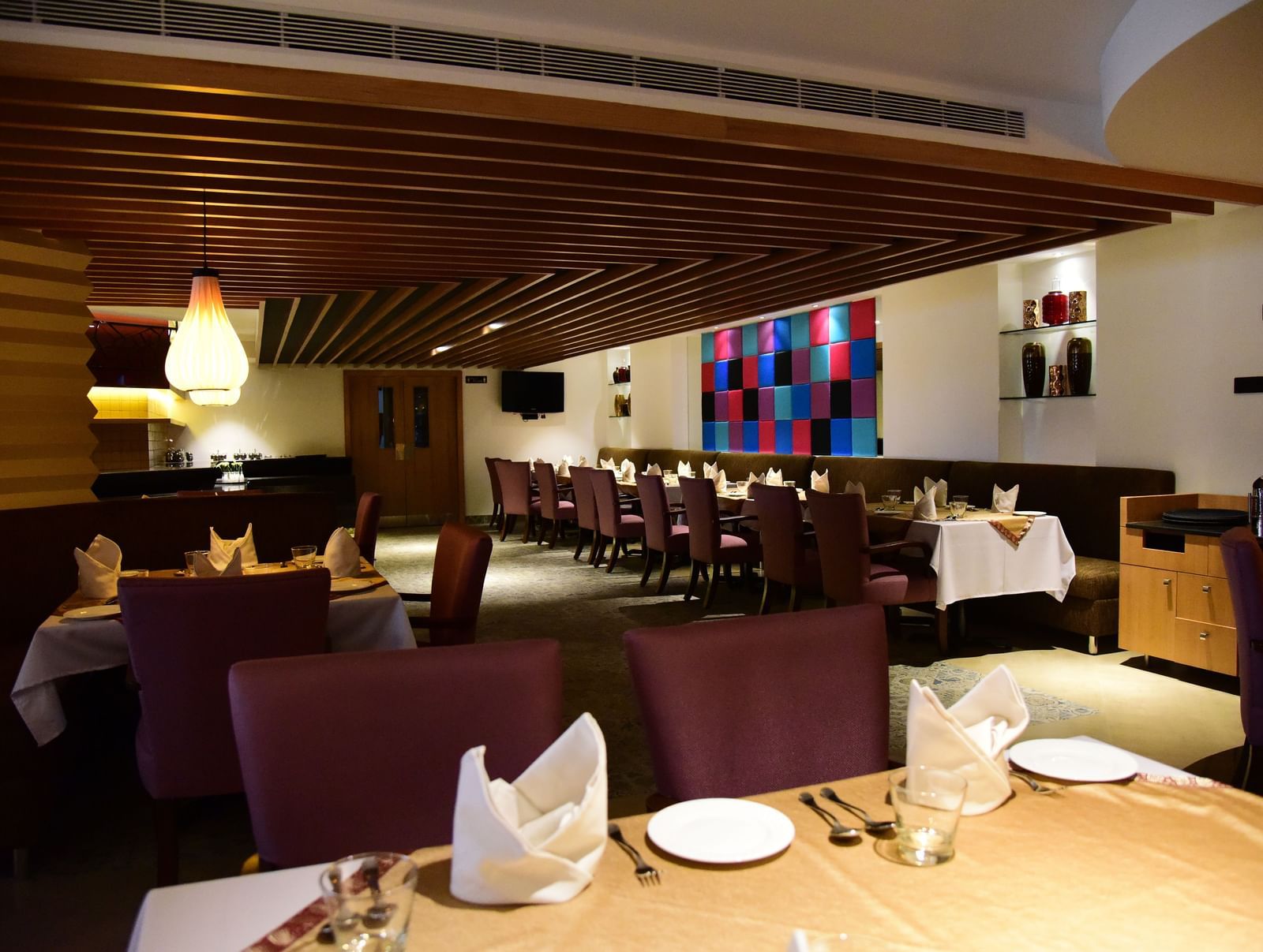 A side-angle shot of a hotel restaurant at The Royal Comfort, with elegant lighting, tables set for dinner, and a warm atmosphere.