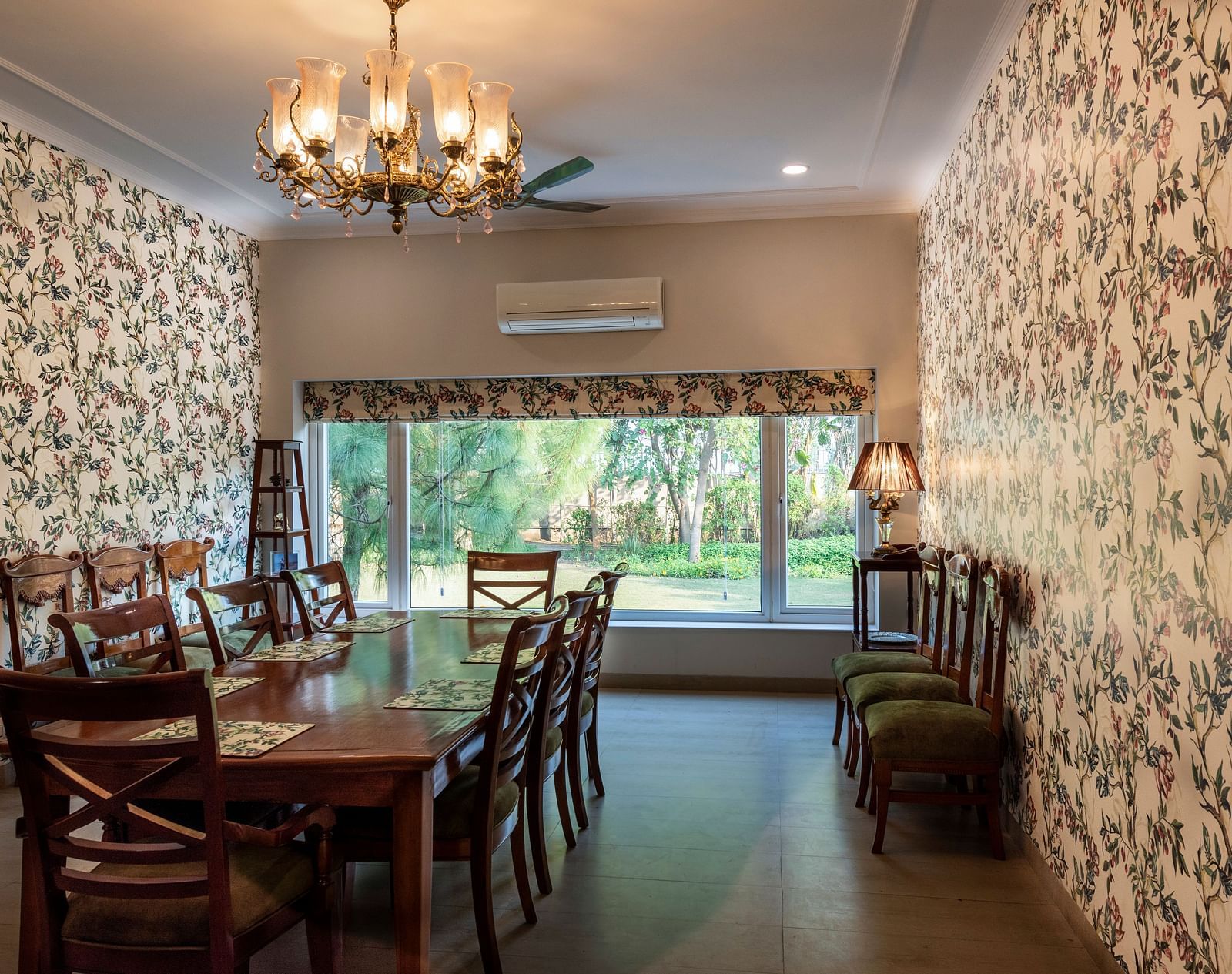 An image of a dining room with floral walls, a chandelier and an AC in the background.
