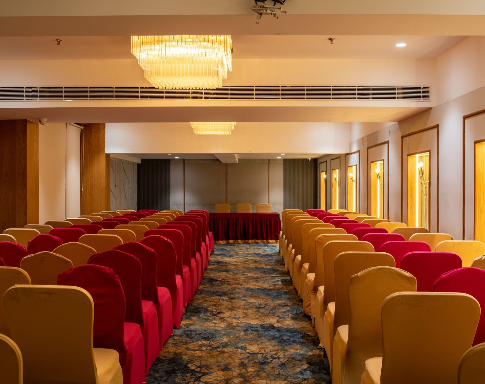 Banquet hall with seating in red and beige chairs at Hotel Royal Regency Chennai
