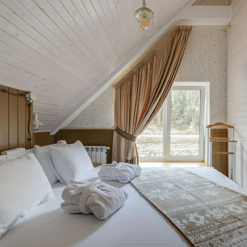 An attic-style room featuring twin beds with white linens on them and a wall-mounted TV.