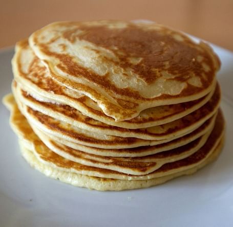 A stack of fluffy pancakes on a white plate.