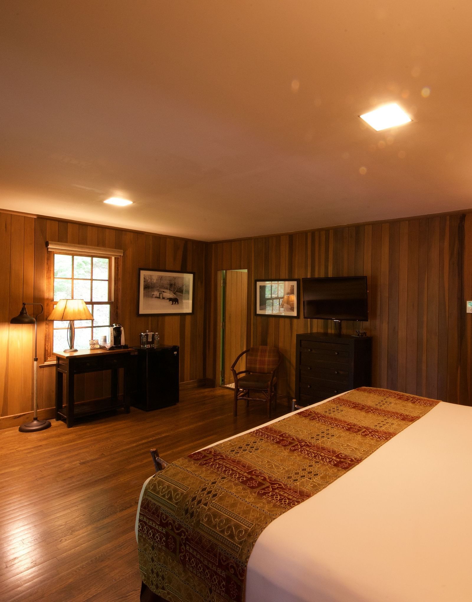 a cozy image of a bedroom with wooden interiors and featuring a double bed and a small window right opposite to it - Historic Tapoco Lodge