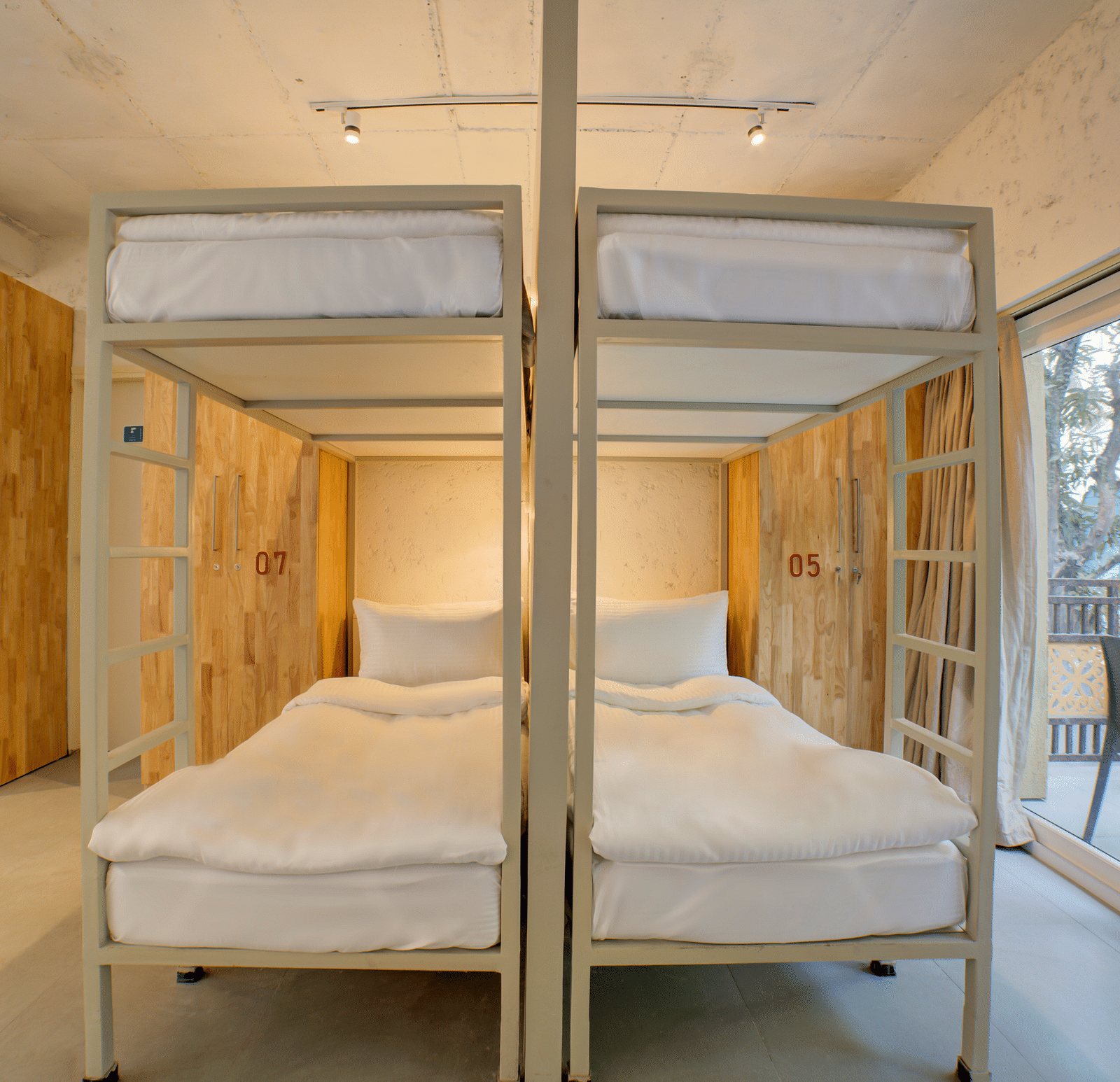 Four Bunk Beds side by side with a large window opening into a balcony on the right side - Bedzzz, Rishikesh