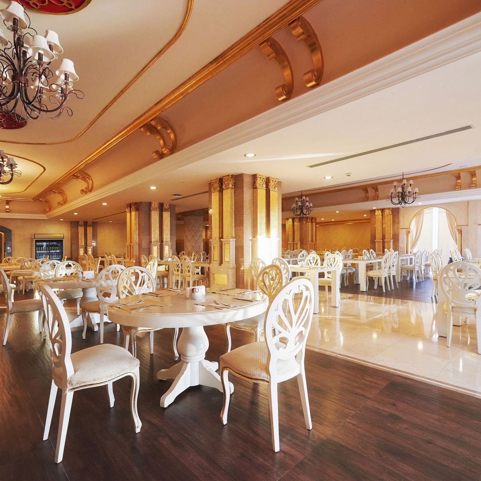 Chairs and tables in a well-lit dining space with dangling chandeliers