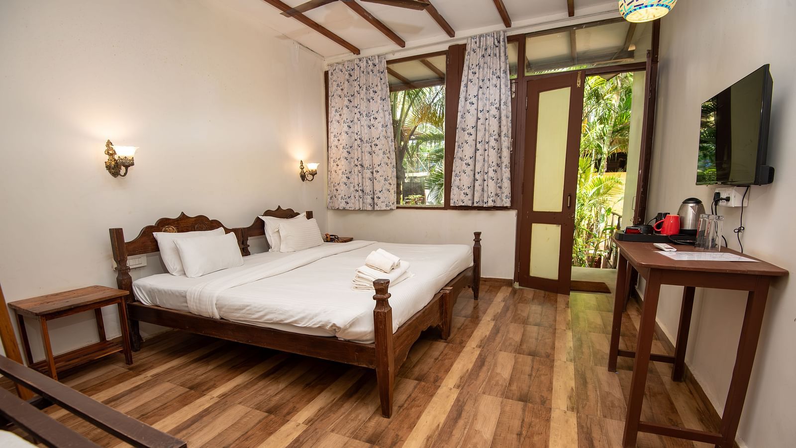 Spacious room with large bed, wooden furniture, and a wall-mounted TV at at De Soul Santé, Morjim.