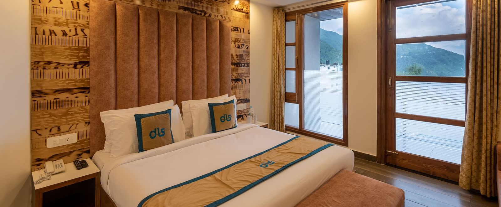 Premium room with a bed, wooden decor, TV, and a balcony offering mountain views - DLS Meghavan Resort, Dharamshala