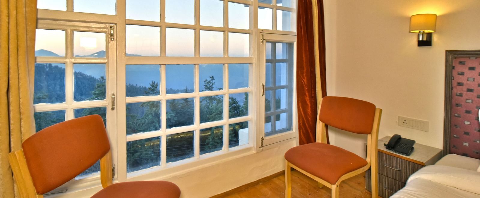 Seating area in the bedroom next to the window at DLS Hillcrest Resort, Shimla.