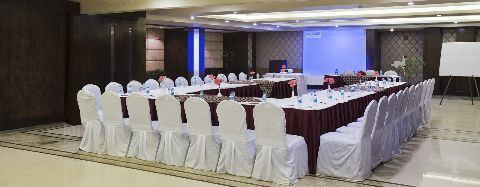 an image of a Conference Hall with chairs and a table with projector screens, and whiteboards at The Manor, Bareilly