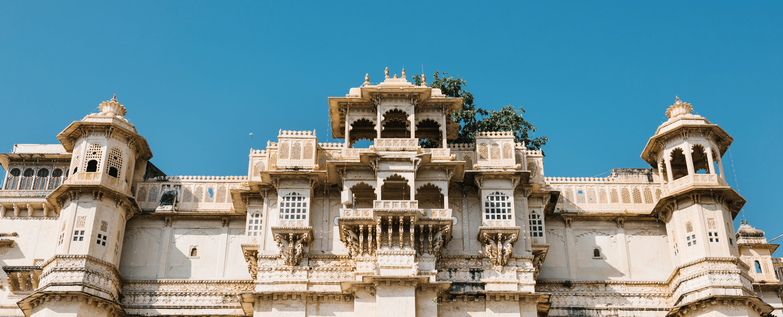 Facade of the City Palace in Udaipur, Rajasthan, featuring balconies and jharokhas against a clear sky