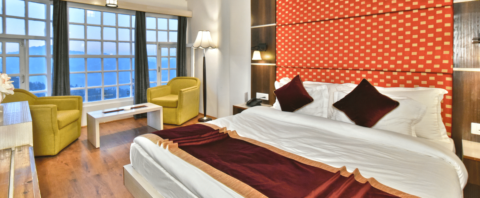 A bedroom with a seating area by the window, offering a mountain view at DLS Hillcrest Resort, Shimla.
