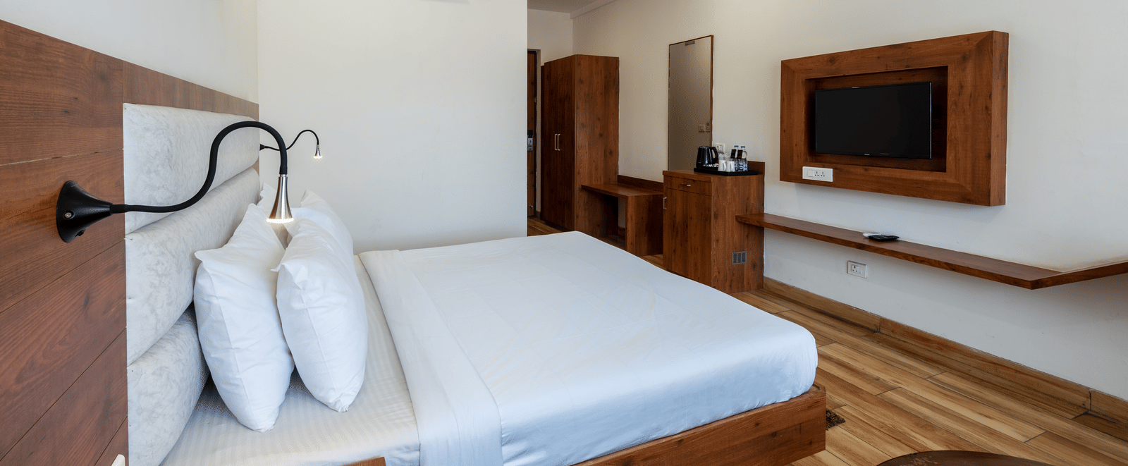 Side view of a Club Balcony Room featuring a bed with a fancy bedside light and a sleek wooden wardrobe in the background at DLS The Classio