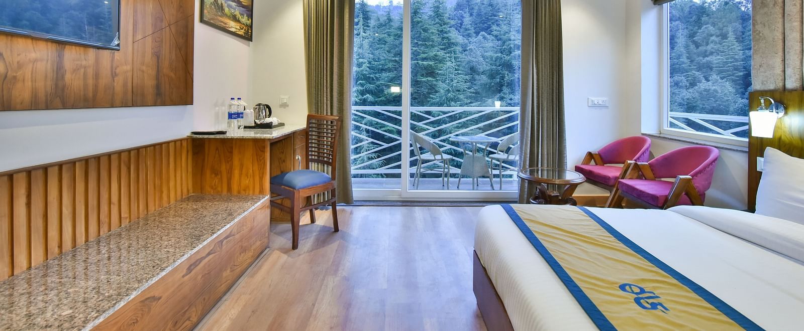 A view of the TV in front of the bed in Premium Room With Balcony at DLS Ark Holiday Inn, Banikhet.