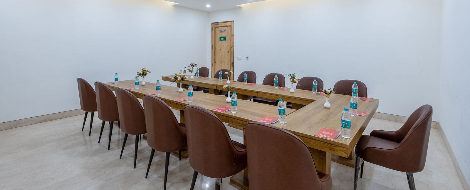Side view of a conference room with multiple chairs, an air conditioner, and water bottles placed on the table at DLS The Classio