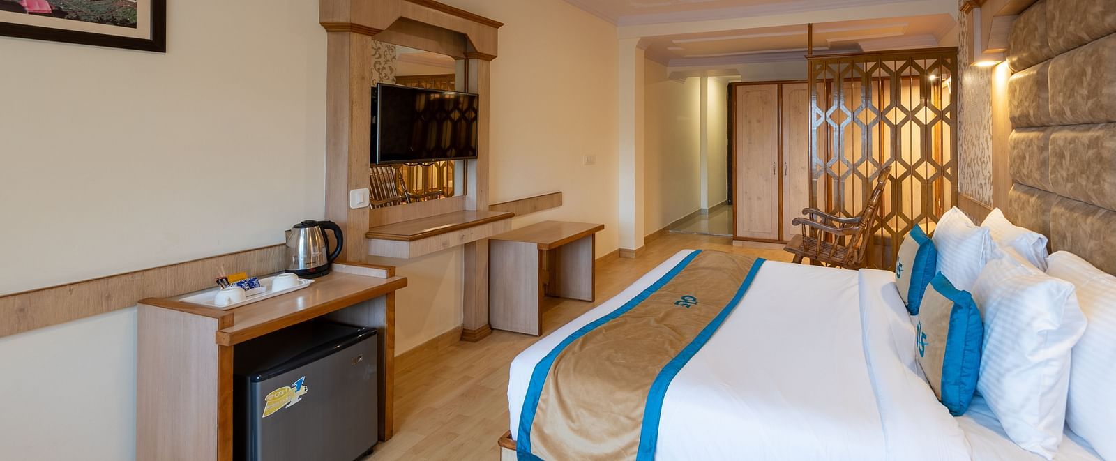 A premium room with a bed, wooden decor, TV, seating area, and scenic views, offering a relaxing and comfortable stay - DLS Meghavan Resort, Dharamshala