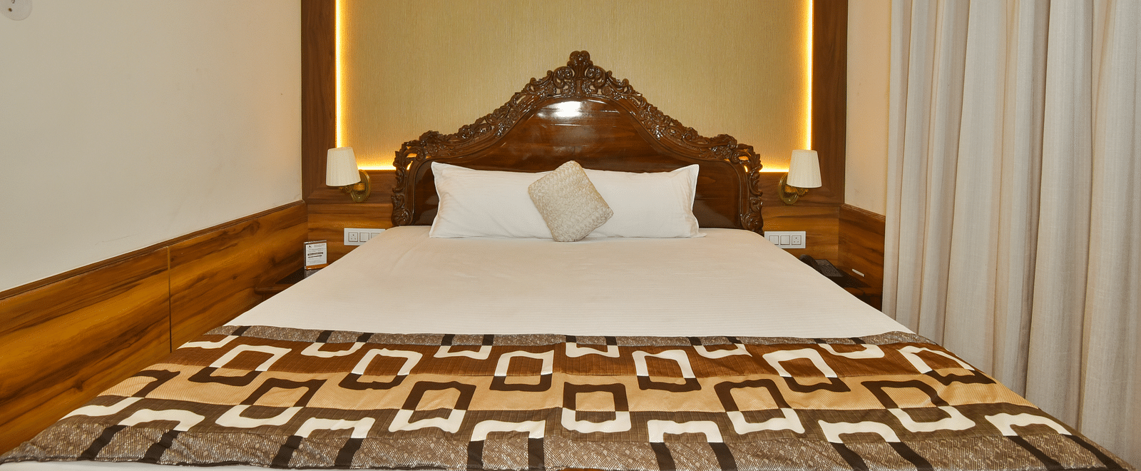 Closeup view of Super Deluxe room at DLS Dalhousie Valley Resort with a  king size bed and warm lighting 