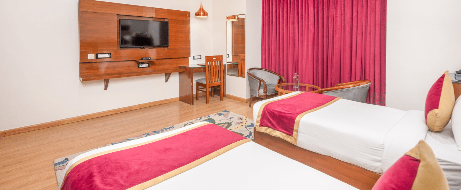 Twin bed room with TV and seating at DLS Hotels On The Ganges.