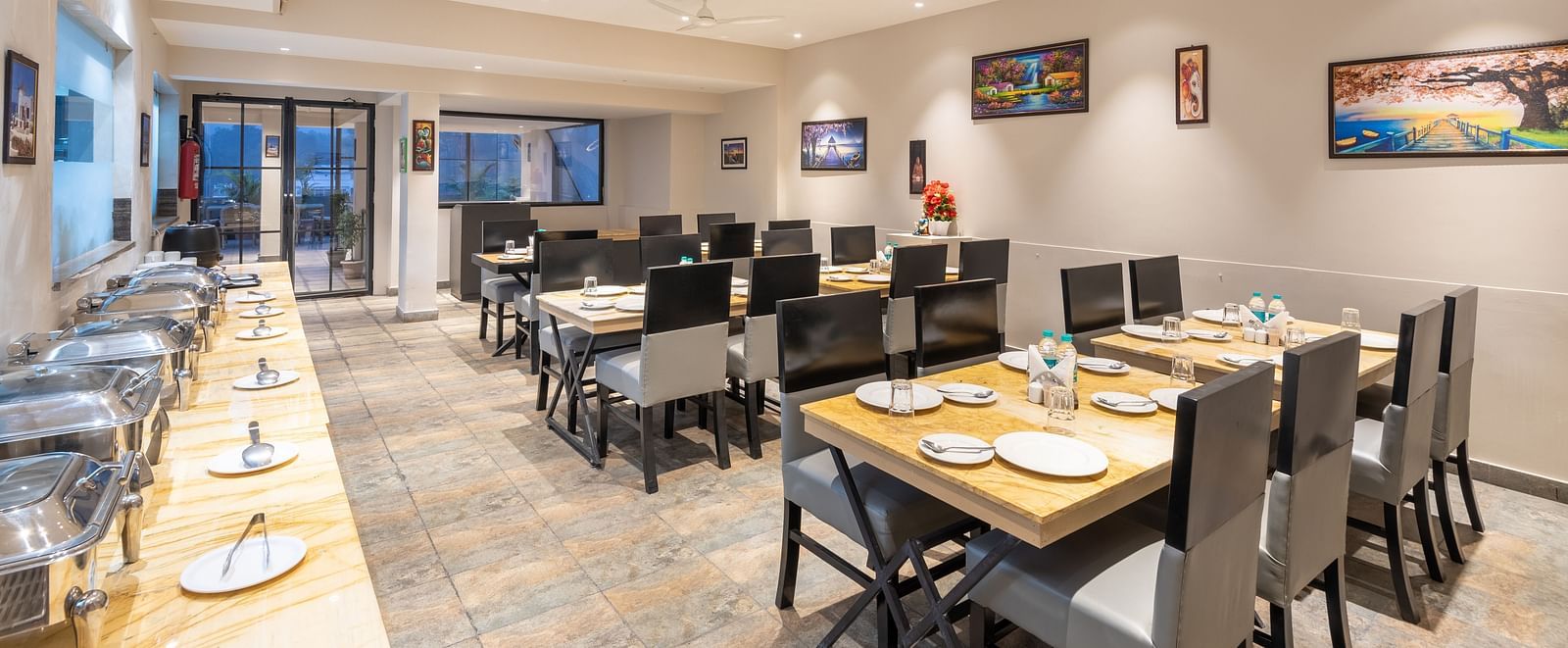 The indoor restaurant set up with chairs and tables along with a buffet table on the left at DLS Hotel Arihant, Haridwar